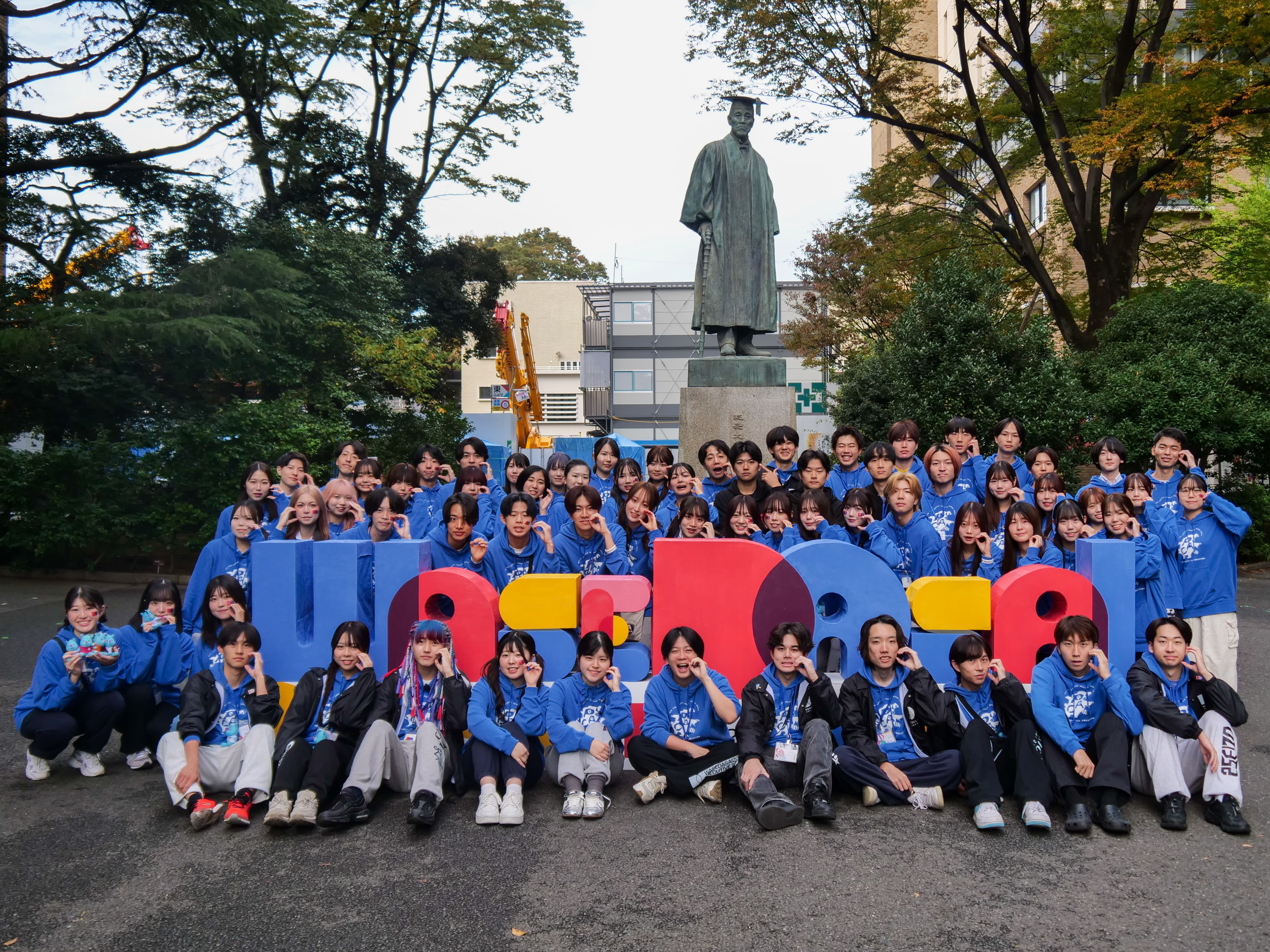 大隈銅像前で写真を撮るスタッフ